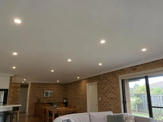 Ceiling with recessed downlights in a brick-walled home interior with dining area and sliding door in Merrimac
